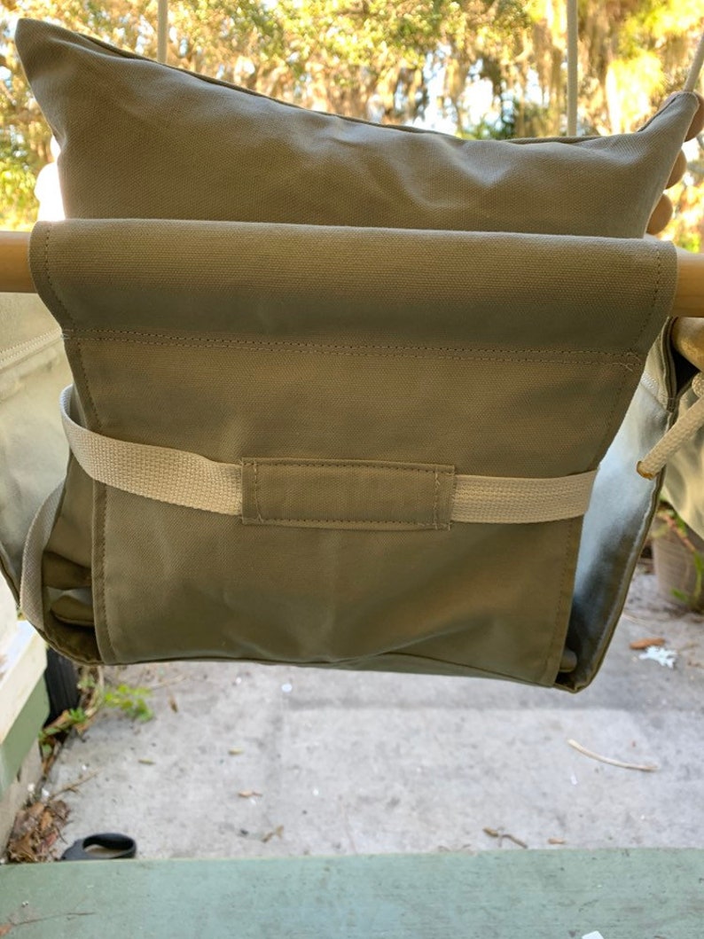 May include: A beige canvas swing seat with a padded back and a strap across the front. The swing is hanging from a wooden frame.