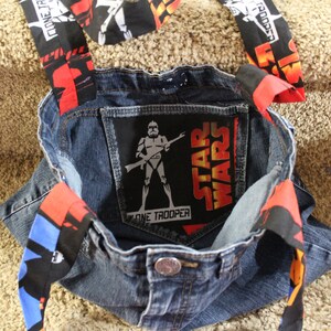 May include: A blue denim tote bag with red, black, and blue fabric straps. The bag has a Star Wars patch on the front with a Stormtrooper and the text "Star Wars" and "Clone Trooper".