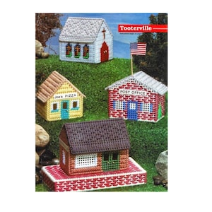Puede incluir: Un conjunto de cinco patrones de lona de plástico para crear casas en miniatura. Los patrones incluyen una iglesia, una pizzería, una oficina de correos y dos casas. Los patrones están etiquetados con los nombres de los edificios y el nombre de la ciudad "Tooterville".