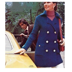 May include: A blue double-breasted blazer with large white buttons. The blazer is knitted and has a pocket on the left side. The model is wearing a pink turtleneck sweater underneath the blazer. The text "BLAZER Number RF-1" is at the bottom of the image.
