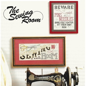 May include: A vintage sewing machine with a wooden base and a red and white cross-stitch sign that reads "Sewing Room". There is a white fabric and a pair of scissors on the table. The sign above the sewing machine reads "Beware of pins and needles. Bare feet enter at their own risk."
