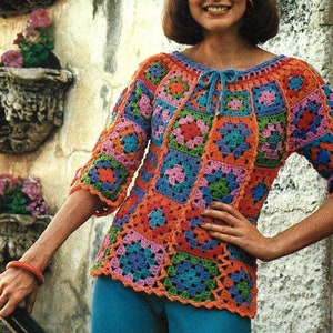 Op de afbeelding: Een kleurrijk gehaakt topje met een vierkant patroon in tinten roze, oranje, groen, blauw en paars. Het topje heeft een strik aan de halslijn en driekwart mouwen.