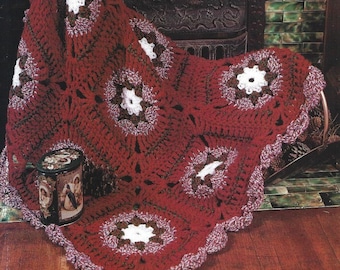 May include: A crocheted throw blanket in shades of red, white, and brown. The blanket features a repeating pattern of large, circular motifs.