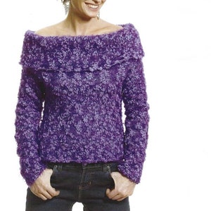 Könnte beinhalten: Ein lilafarbener Strickpullover mit einem weiten, off-shoulder-Ausschnitt. Der Pullover hat eine strukturierte, flauschige Optik.