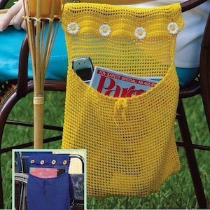 Op de afbeelding: Twee gele gehaakte tassen met daisy-versieringen. De tassen hangen aan de rugleuningen van stoelen. Eén tas is gevuld met een tijdschrift en een mobiele telefoon. De andere tas is leeg.