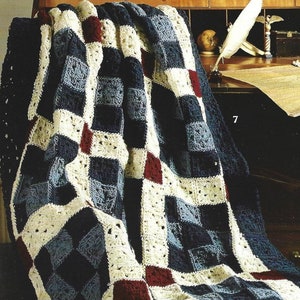 Puede incluir: Una manta de ganchillo con un patrón de cuadros en tonos de azul, blanco y rojo. La manta está colocada sobre una silla.