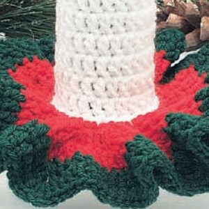 May include: A crocheted Christmas tree skirt with a white base and green and red ruffled edges.
