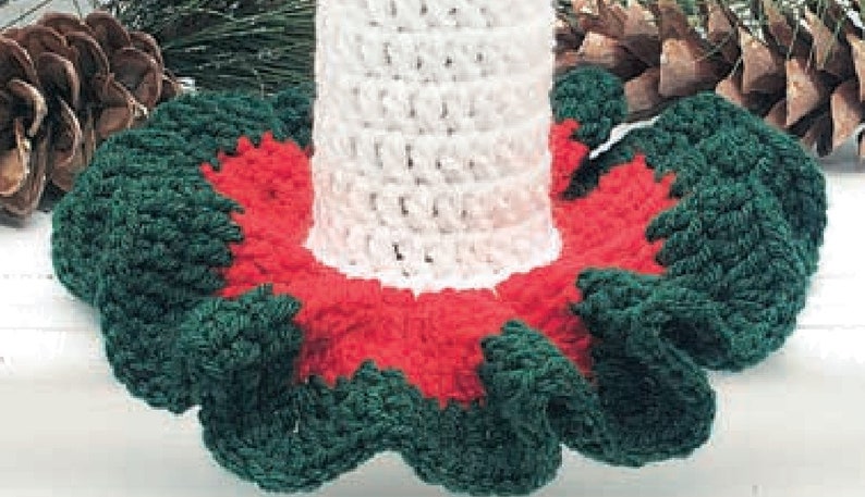 May include: A crocheted Christmas tree skirt with a white base and green and red ruffled edges.