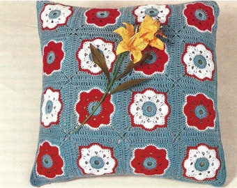 May include: A blue, red, and white crocheted pillow with a flower pattern. The pillow is decorated with a yellow lily.