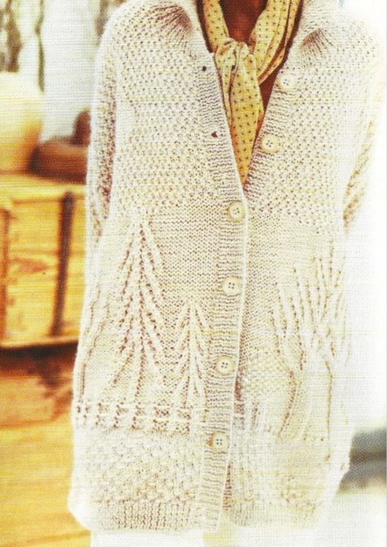 May include: A cream knitted cardigan with a button-up front and a delicate lace pattern. The cardigan has a V-neck and long sleeves.