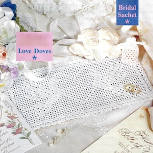 Könnte beinhalten: Ein weißer gehäkelter Braut-Sachet mit dem Text "Bridal Sachet" in blauer Schrift. Der Beutel ist umgeben von weißer Spitze, einer weißen Porzellan-Taubenfigur und einer rosa Karte mit dem Text "Love Doves" in blauer Schrift.