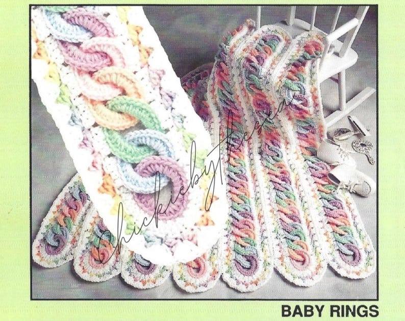 May include: A crocheted baby blanket with a white background and colorful rings. The blanket is made with a variety of colors, including pink, blue, green, and yellow. The blanket is folded in half and is sitting on a white rocking chair. The text "BABY RINGS" is printed at the bottom of the image.