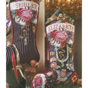 以下が含まれることがあります： 「Shirley」と「Elizabeth」という名前が刺繍された、花柄のクリスマスストッキング2つ。ビーズ、リボン、小さな天使の置物で飾られています。