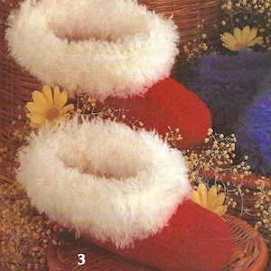 May include: A pair of red slippers with a fluffy, cream-colored trim. The slippers are displayed on a woven basket, with a yellow flower and dried floral accents. The number "3" is visible on the basket.