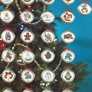 Peut inclure: Un ensemble de 12 d&eacute;corations de No&euml;l sur le th&egrave;me des f&ecirc;tes, comprenant un bonhomme en pain d'&eacute;pices, une colombe, un bonhomme de neige et un renne. Chaque d&eacute;coration est un cercle blanc avec un ruban rouge et un num&eacute;ro de 1 &agrave; 12.
