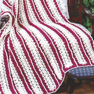 May include: A handmade crochet blanket with alternating vertical stripes of cream and burgundy. The blanket is draped over a wooden chair, showcasing its textured pattern and detailed edging. The cozy design suggests a warm, comforting aesthetic.