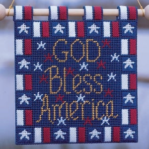 Könnte beinhalten: Ein blaues und rotes Stoffbanner mit weißen Sternen und den Worten "God Bless America" in goldenen Buchstaben.