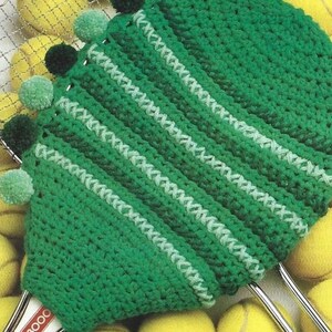 May include: Green crocheted tennis racket cover with white stripes and pom-poms around the edge.