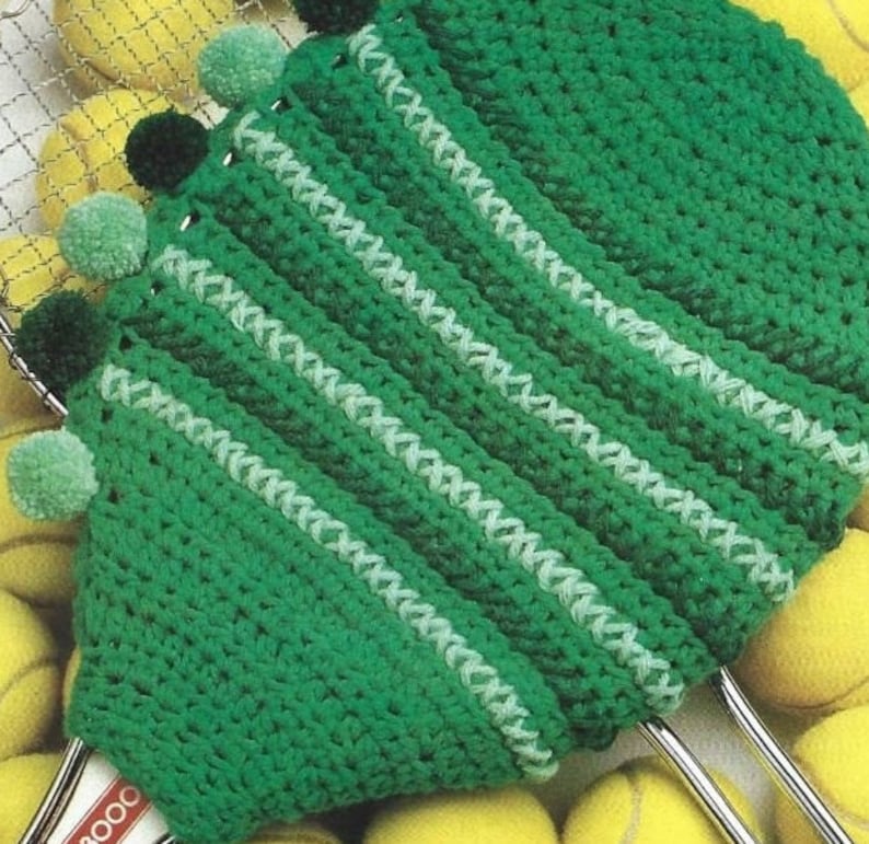 May include: Green crocheted tennis racket cover with white stripes and pom-poms around the edge.