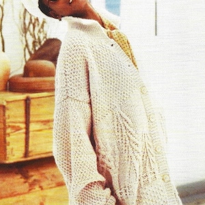 May include: A light beige knitted cardigan with a cable knit pattern and button closure. The cardigan is oversized and has a relaxed fit.