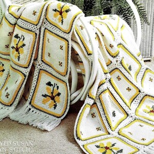 May include: A white crocheted throw blanket with yellow and brown squares featuring a flower design. The blanket has fringe on the edges. "Brown-Eyed Susan in Afghan Stitch" is written on the bottom of the image.