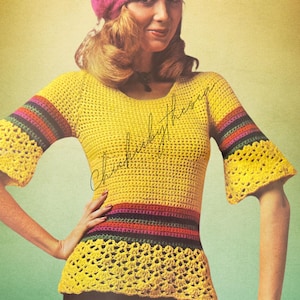 Puede incluir: Un top de crochet amarillo con rayas arcoíris y una manga acampanada de crochet. El top tiene un ribete de crochet alrededor de la parte inferior. La modelo lleva una boina rosa.