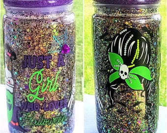 May include: A black and green glitter tumbler with a purple lid. The tumbler has a witch with a skull and crossbones on one side and the text "Just a Girl Who Loves Halloween" on the other side.