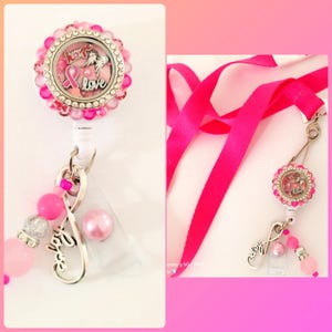 May include: Pink and silver charm with a pink ribbon and the words "Hope Love" inside a clear circle. The charm is attached to a pink retractable badge holder with a silver infinity symbol charm and pink beads.