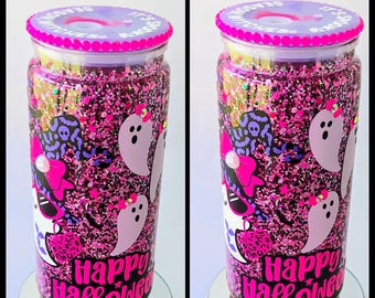 May include: A Halloween-themed tumbler with a pink glitter background. The tumbler features cartoon ghosts, witch graphics, and the words "Happy Halloween" in pink. The lid is purple with the text "It's the season for witches".