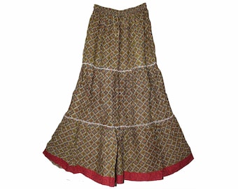 May include: A long, tiered skirt with a repeating floral pattern in shades of olive green, brown, and white. The skirt has white trim between the tiers and a red border at the hem. The skirt is made of a lightweight fabric.