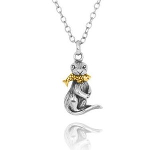 May include: Silver necklace with a silver and gold otter pendant holding a gold fish in its mouth.