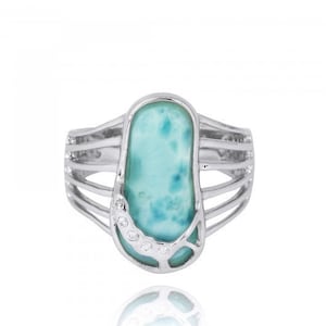 May include: A silver ring with a blue and green gemstone set in a silver setting. The gemstone is surrounded by small clear stones.