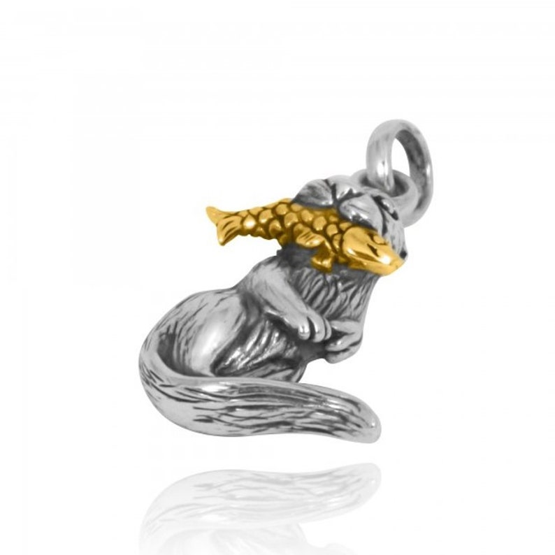 May include: A silver charm of a cat holding a gold fish in its mouth. The charm is detailed and has a realistic look.