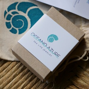 May include: A small, brown cardboard box with a white label that says "Oceano Azure Sea Life Jewelry". The label features a stylized seashell design.
