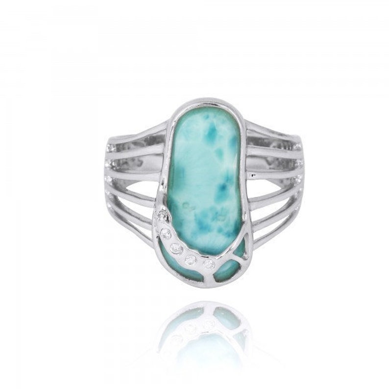 May include: A silver ring with a blue and green gemstone set in a silver setting. The gemstone is surrounded by small clear stones.