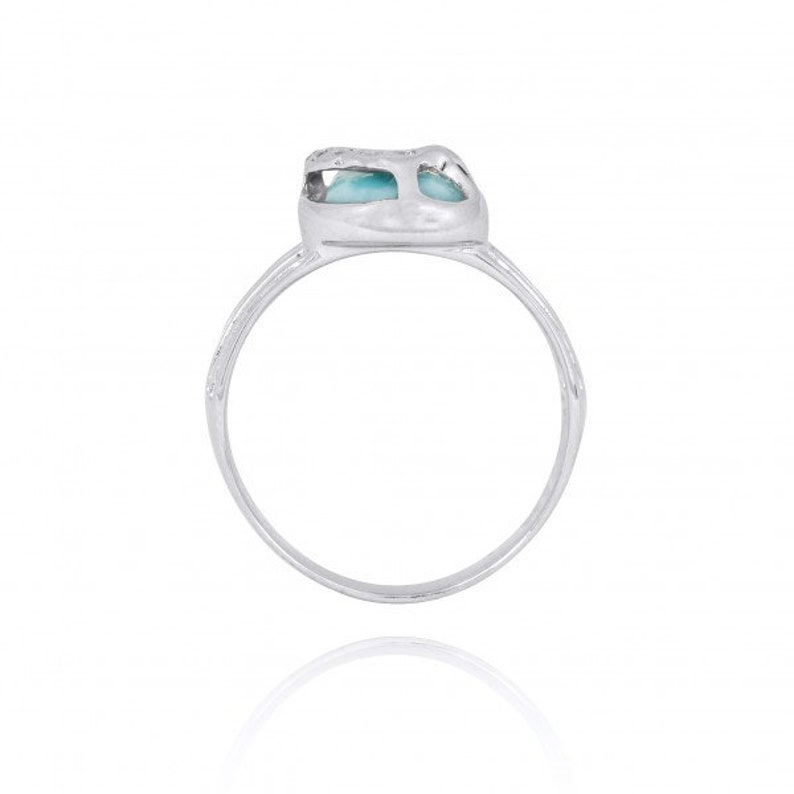 May include: A silver ring with a blue gemstone set in a heart-shaped design.