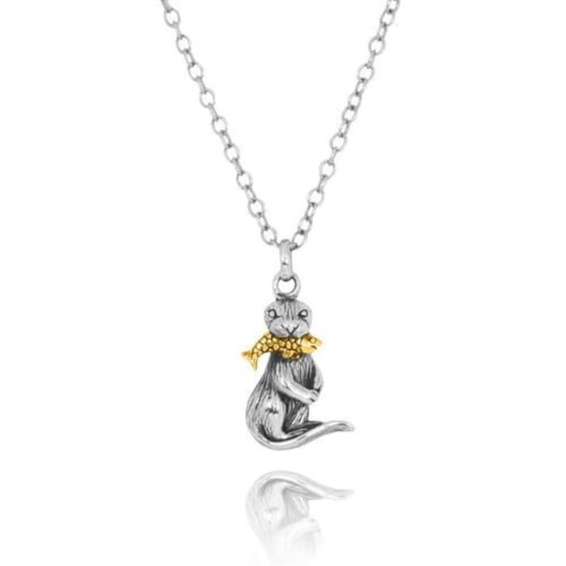 May include: Silver necklace with a silver and gold otter pendant holding a gold fish in its mouth.