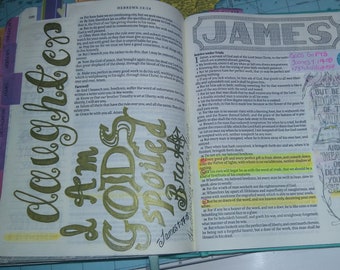 Peut inclure: Une page de la Bible avec des notes manuscrites et des illustrations. La page présente le texte "Jacques 1:1-18" et les mots "GODS GIFTS" et "BUT BE YE DOERS OF THE WORD". La page est décorée de lettres dorées et d'un dessin d'un oiseau.