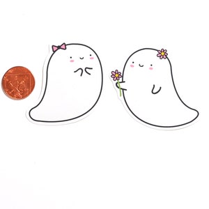May include: Two cartoon ghosts, one with a pink bow and the other with a pink flower, are smiling at each other. The ghost on the right is holding a pink flower.