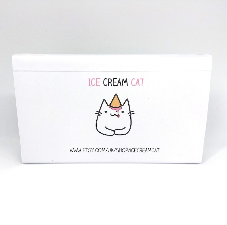Puede incluir: Caja blanca con un gato de dibujos animados que lleva un cono de helado en la cabeza. El texto "ICE CREAM CAT" est&aacute; por encima del gato y "www.etsy.com/uk/shop/icecreamcat" est&aacute; por debajo del gato.