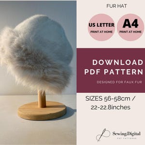 May include: A white faux fur hat displayed on a wooden stand. The image includes text that reads "FUR HAT", "DOWNLOAD PDF PATTERN", and "SIZES 22-22.8 inches". The pattern is designed for faux fur.