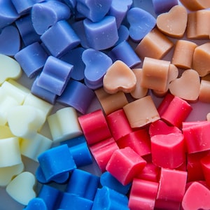 May include: Assortment of heart-shaped wax melts in various colours, including white, light blue, purple, pink, and red.
