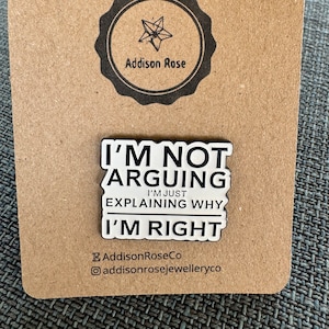 Puede incluir: Pin de esmalte blanco con texto negro que dice "No estoy discutiendo, solo estoy explicando por qué tengo razón". El pin está en una tarjeta marrón con el logotipo "Addison Rose" en un círculo.