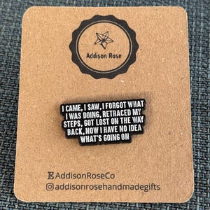 Puede incluir: Pin de esmalte negro con texto blanco que dice "Vine, vi, olvidé lo que estaba haciendo, retrocedí mis pasos, me perdí en el camino de regreso, ahora no tengo idea de lo que está pasando".