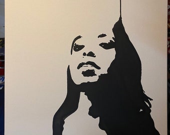 May include: A black and white portrait painting of a woman's face and hair. The artwork is a minimalist design with the woman's features and hair in solid black against a white background. The painting is on a canvas.