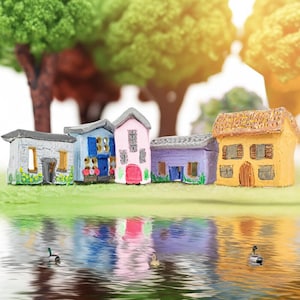 May include: A set of miniature, brightly coloured houses, each with distinct architectural features. The houses are painted in shades of grey, blue, pink, purple, and yellow. The scene includes a reflective water surface with ducks and a backdrop of green trees.