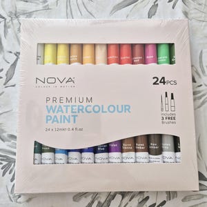 May include: A boxed set of 24 premium watercolor paints in various colors, each tube containing 0.4 fl oz of paint. The box includes three free brushes and features the text "PREMIUM WATERCOLOUR PAINT".