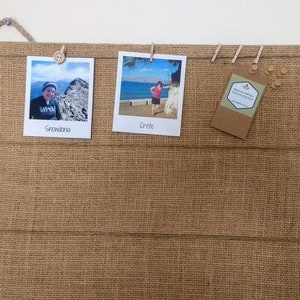 Puede incluir: Un tablero de anuncios de arpillera con tres fotos y una etiqueta fijada a &eacute;l. Las fotos son de una persona en Snowdonia y una persona en Creta. La etiqueta dice "Handmade with love for MODERN EAT".