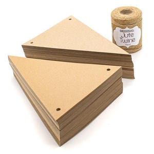 May include: Two stacks of triangular brown kraft paper pennants, each featuring two pre-punched holes at the top corners. Beside the stacks sits a spool of brown jute twine with a label that reads Original Jute Twine 75mt.