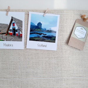 May include: A natural burlap memo board displays two travel photos, one of Madeira and one of Scotland, held by small wooden clothespins. A brown tag with the text "WOODKRAZY" and wooden push pins are also attached.